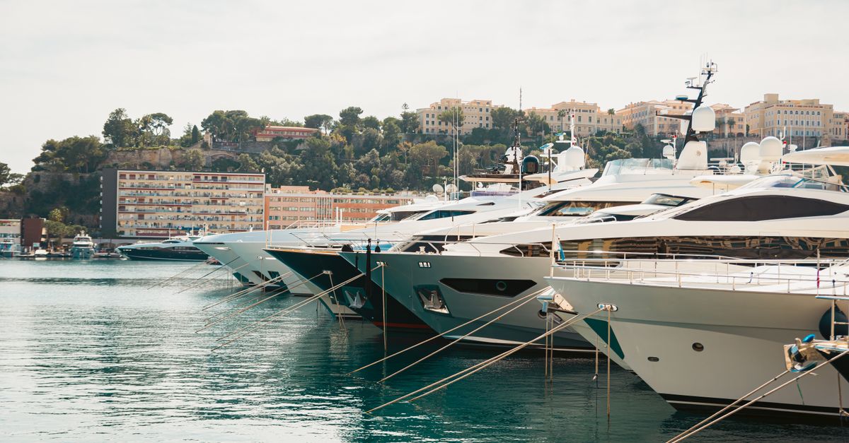 A scenic view of luxury yachts moored in Monaco harbor with cityscape in the background.